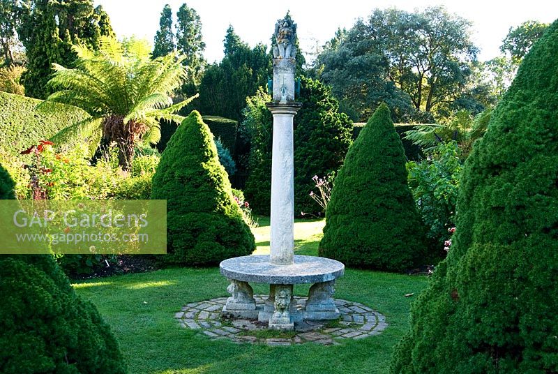 The Sundial Garden with late afternoon sun illuminating tree ferns, conical Piceas and exotic herbaceous plants including Salvias, Dahlias and Ricinus - Exbury Gardens, Exbury, Hants, UK