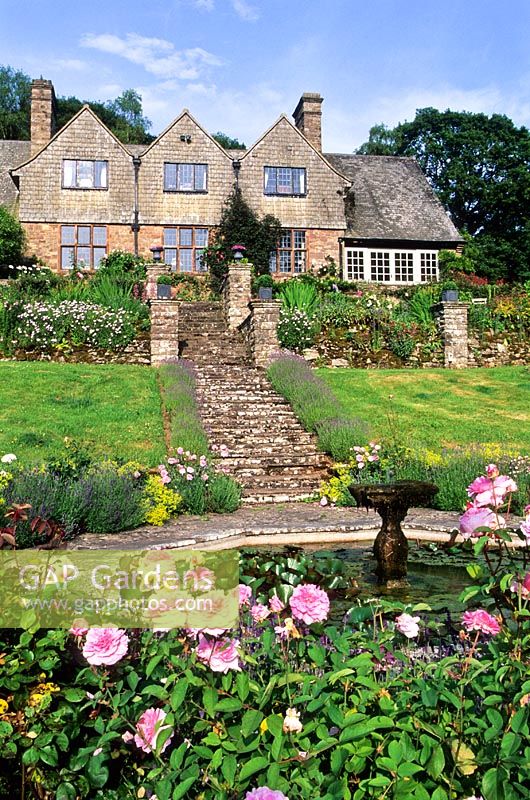 View to house and terraces from Octagonal pool. Rosa 'Mary Rose' in foreground - High Glanau Manor, Monmouthshire, Wales 
 