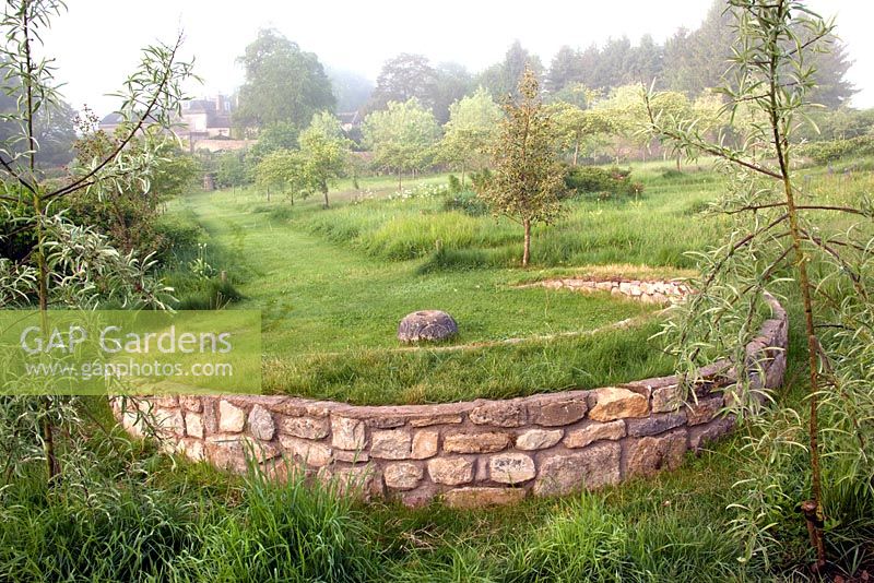 Grass path in the meadow leading to a grass covered stone horse-shoe shaped seat - Somerset Lodge 
