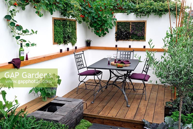 Alfresco dining area in a contemporary small garden, with scented herbs planted in vertical wall boxes. 