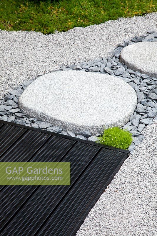 Detail of granite stones and gravel path leading to a wooden area in the Japanese themed garden - 'Less and More' garden - RHS Hampton Court Flower Show 2011
 