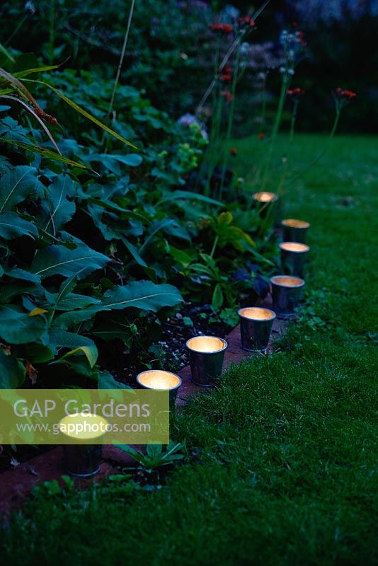 Garden lighting - small zinc candle holders edging a flower bed