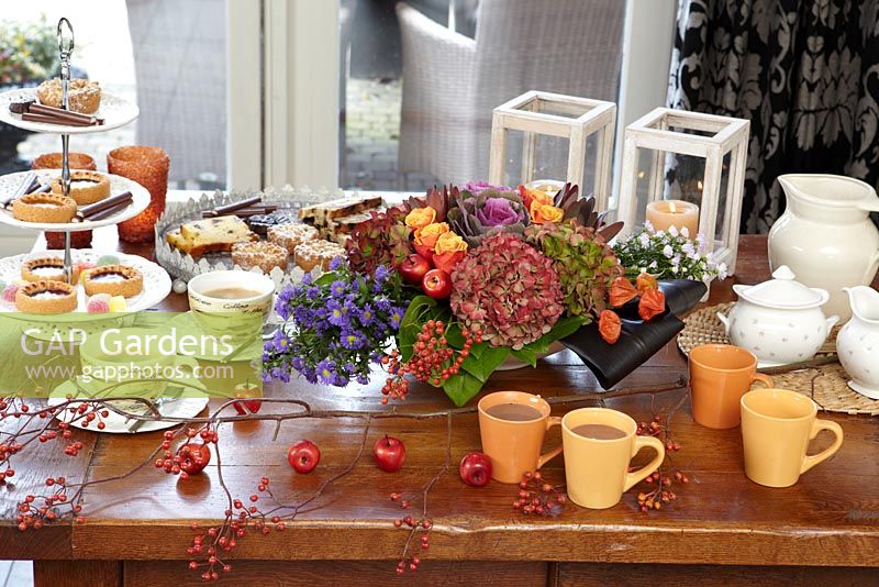 Floral arrangement on coffee table with tea and cakes