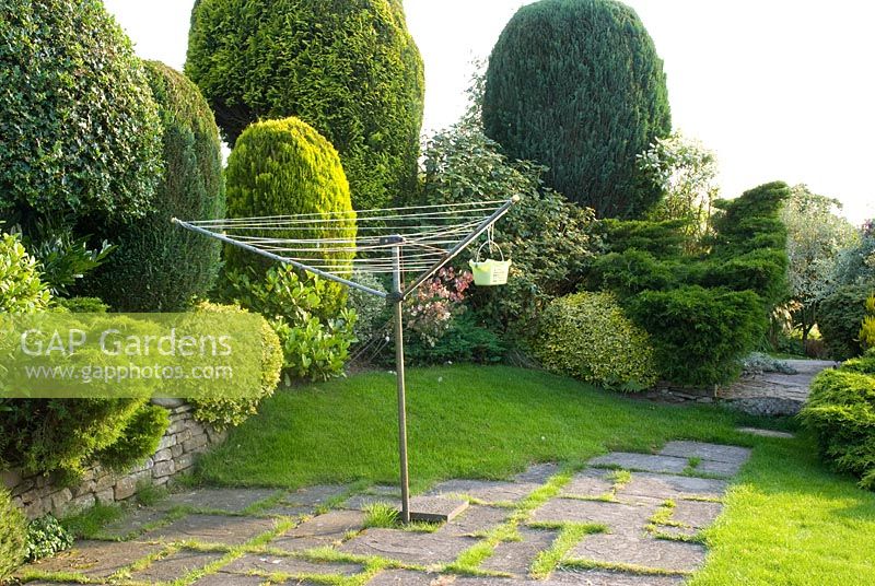 Rotary clothes line on flagged area with raised bed containing mixed conifers and shrubs - Hillside Cottage, Pott Shrigley, Cheshire NGS