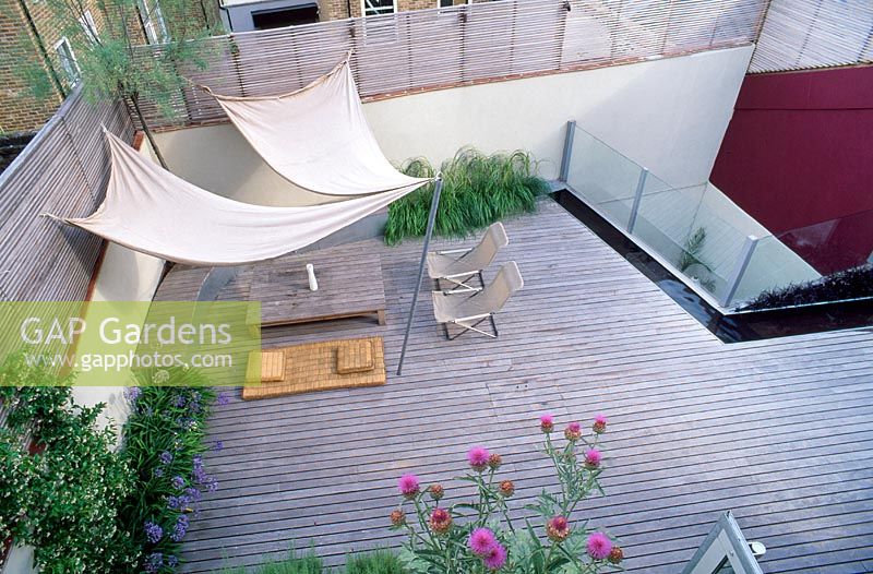 Roof garden with timber decking, awning, deckchairs, slatted trellis, kauna rush mattress, water rill, steel container with globe artichokes