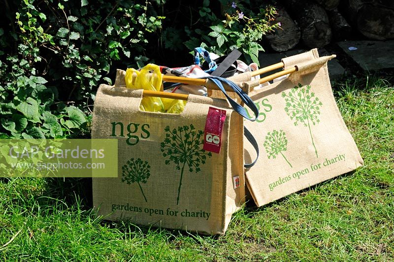 Jute shopping bags on grass with National Garden Scheme, gardens open for charity printed on the side