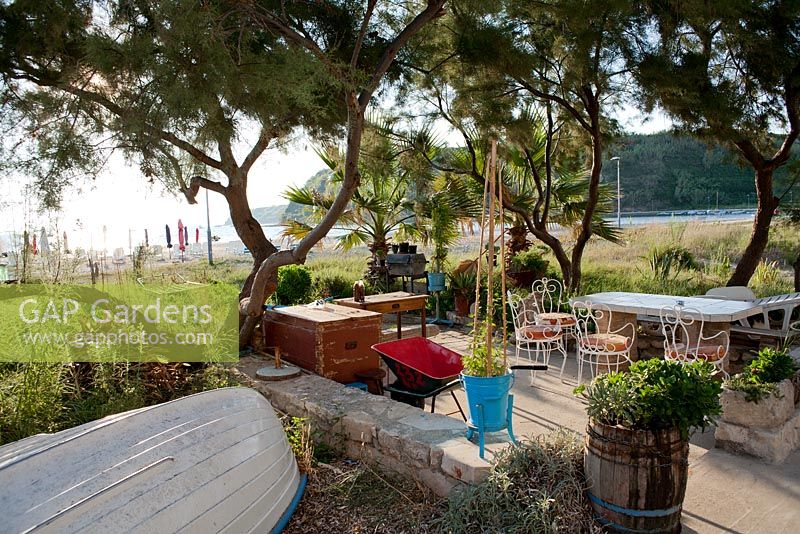 Patio in Mediterranean coastal garden with old fishing boat
