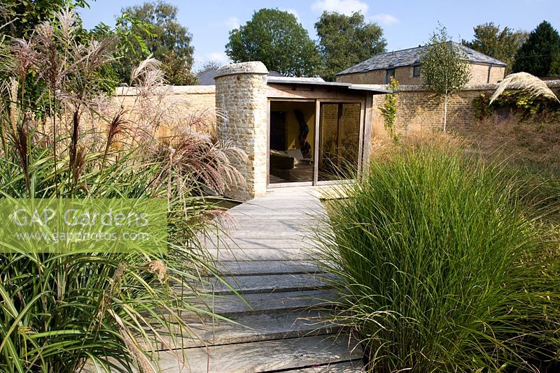 Garden view of the summerhouse with Miscanthus 'Malepartus' and 'Gracillimus' - Farrs, Dorset