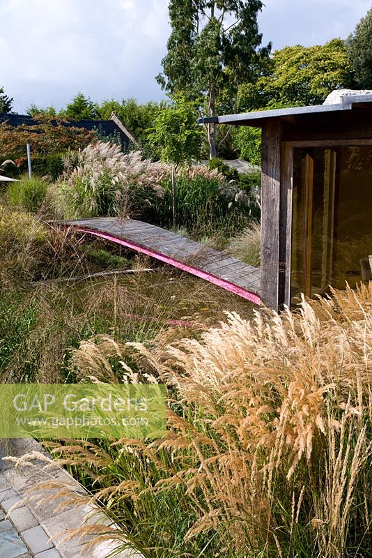 Garden view of summerhouse with Stipa calalmagrostis and Molinia 'Transparent' - Farrs, Dorset