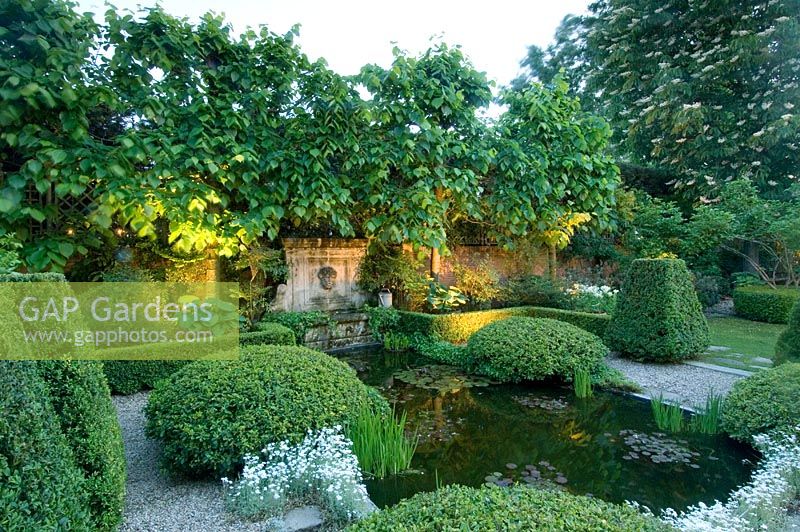 Formal style Mediterranean garden with low box hedge surrounding pond, topiary, lighting, gravel paths and pleached limes - Madrid, Spain