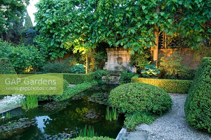 Formal style Mediterranean garden with low box hedge surrounding pond, topiary, lighting, gravel paths and pleached limes - Madrid, Spain