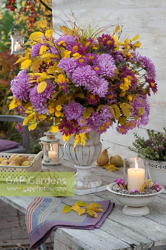 Autumn flower arrangement and candles on garden table 