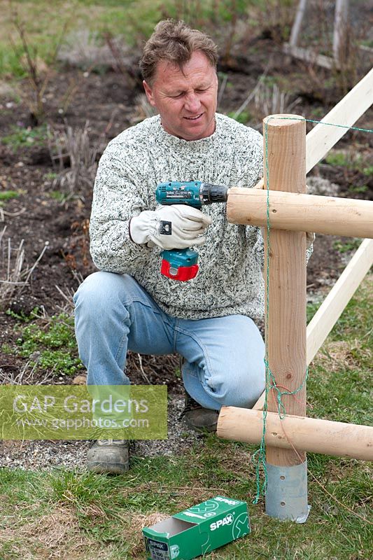 Man building a wooden fence