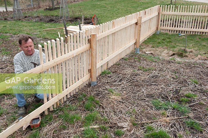 Man building a wooden picket fence