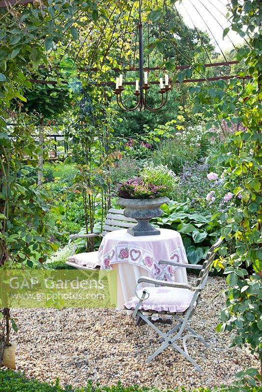 Seating area on gravel, surrounded by climbing roses - Tropical Touch