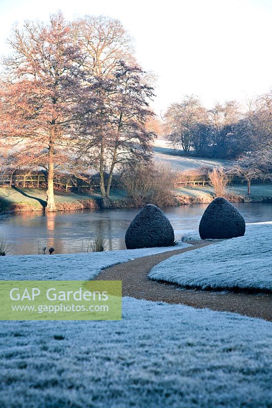 Pathway down to lake in large country garden in February 