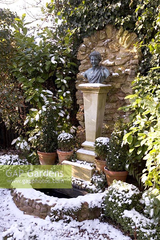 Formal garden with sculpture and water feature in snow - The Old School House, Great Bentley, Essex in January 