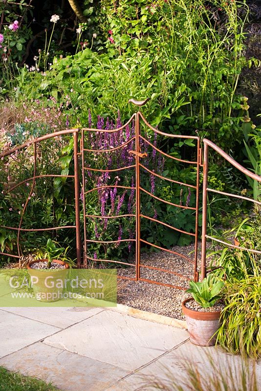 Rusty metal railings and gate with bird ornament on top
