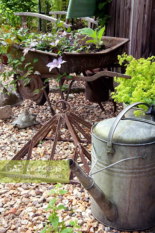 Old garden artefacts including a galvanised watering can, wheel barrow and top of a cold frame used for decoration