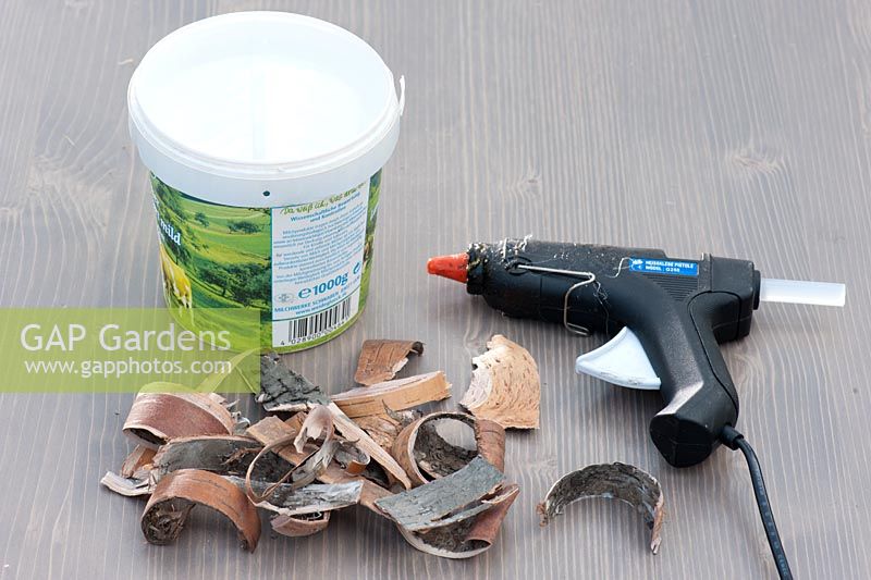 Materials for crafts project - glue gun, old yoghurt pot and  Birch bark chippings