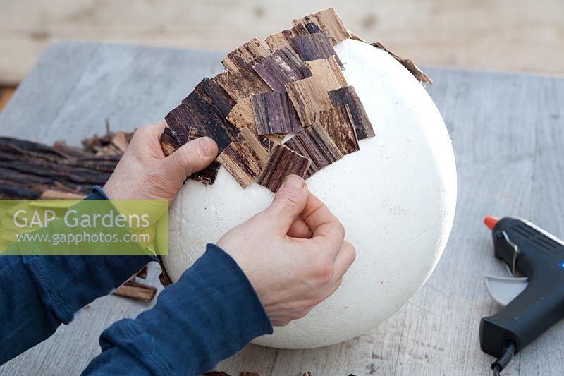 Person sticking bark to bowl 