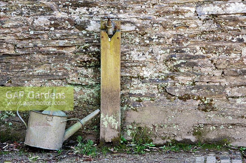 Watering can next to water tap in the Lost gardens of Heligan, Cornwall, England