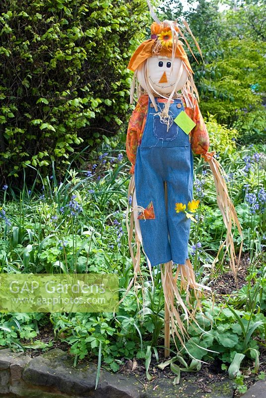 Colourful scarecrow in garden border