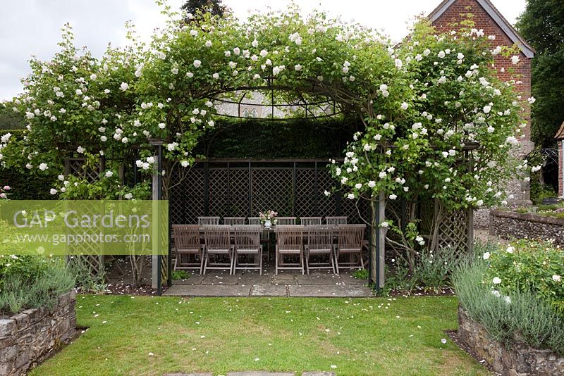 Wooden furniture in gazebo with climbing Rosa - The Flint House
