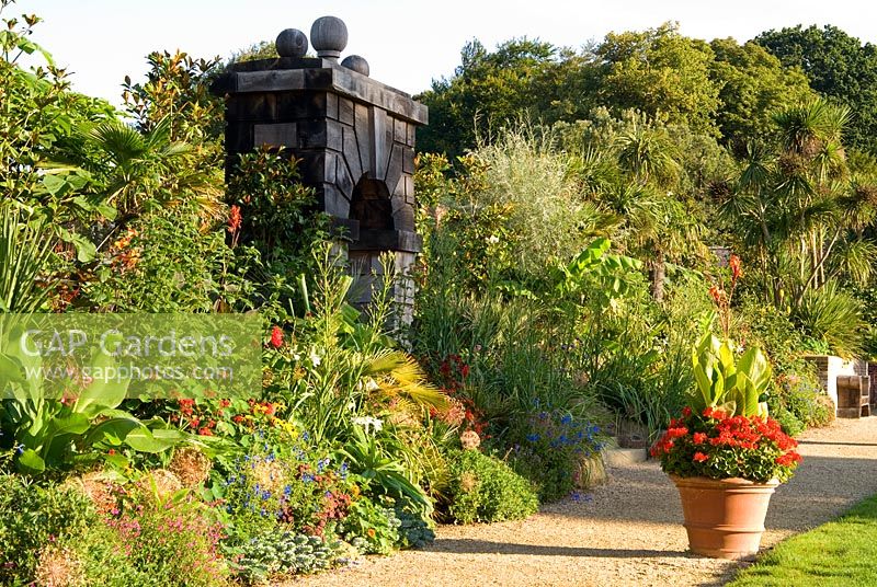 Exotic planting in the Collector Earl's Garden, designed by Julian and Isabel Bannerman, includes echiums, monardas, salvias, eryngiums and rudbeckias. Large terracotta pots punctuate the path planted with red pelargoniums and cannas. 