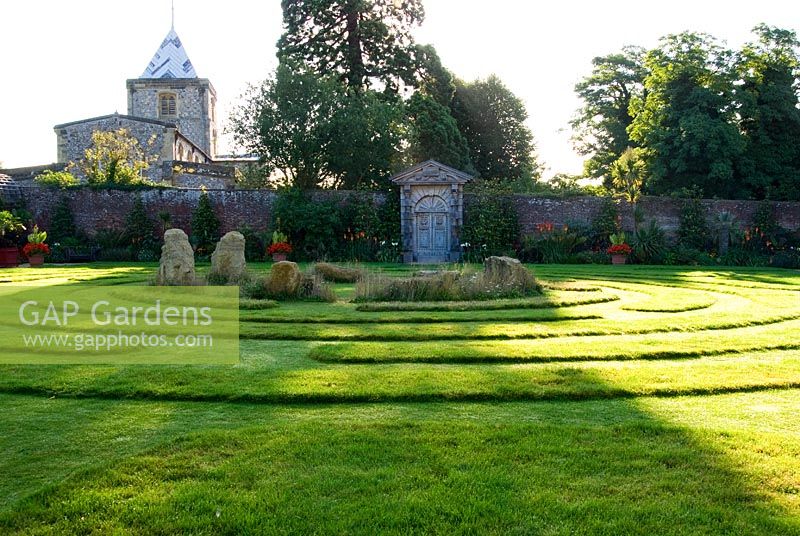 A grass maze with central stones occupies the centre of the Collector Earl's Garden, designed by Julian and Isabel Bannerman, with the Fitzalan Chapel seen beyond.