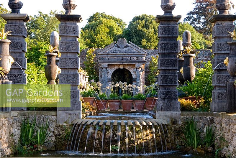 The allegorical River Arun emerges from a rocky grotto framed by a scallop shell pediment and muscular caryatids. It flows along a rill pool flanked by turned oak urns spouting water through gilded lions' heads, with golden agaves in their tops. and spills over a scallop edged cascade into a pool below. The Collector Earl's Garden designed by Julian and Isabel Bannerman.