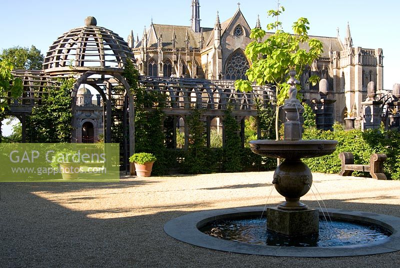 A double domed pergola of oak divides the upper and lower areas of the Collector Earl's Garden. The Upper terrace features fountains with dogs' head spouts, hornbeam hedges and large terracotta pots, with dramatic backdrop of Arundel Cathedral behind. Designed by Julian and Isabel Bannerman.