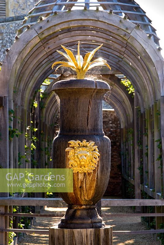 Carved oak urns with gilded lions' heads and agaves with domed pergola beyond in the Collector Earl's Garden designed by Julian and Isabel Bannerman.