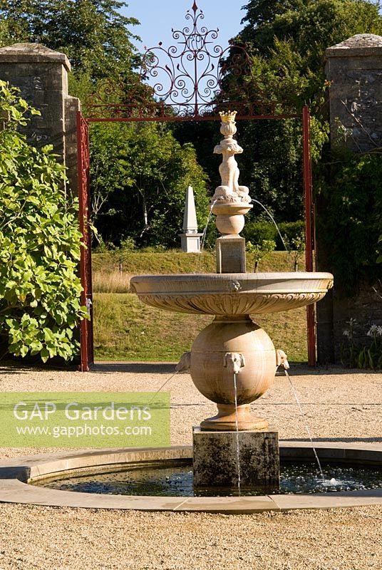 Upper terraces in the Collector Earl's Garden feature fountains with dogs' head spouts, designed by Julian and Isabel Bannerman, with white obelisk glimpsed beyond. 