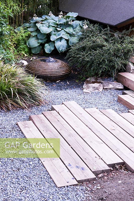 Cross beam pathway set in gravel and small water feature