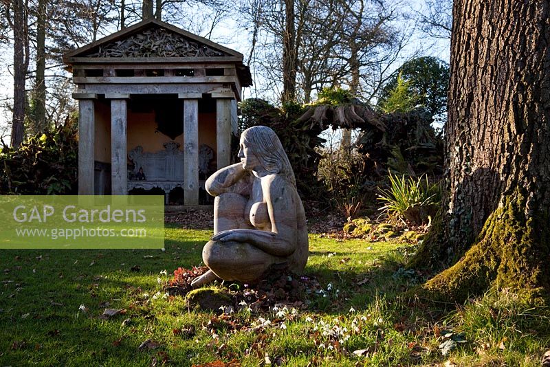 'Goddess of the Woods' sculpture and one of the two green oak temples in the Stumpery, Highgove Garden, February 2011. 