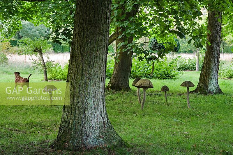 Wooden mushroom sculptures and wooden dog sculpture in the Stumpery. Highgrove Garden, August 2007.   