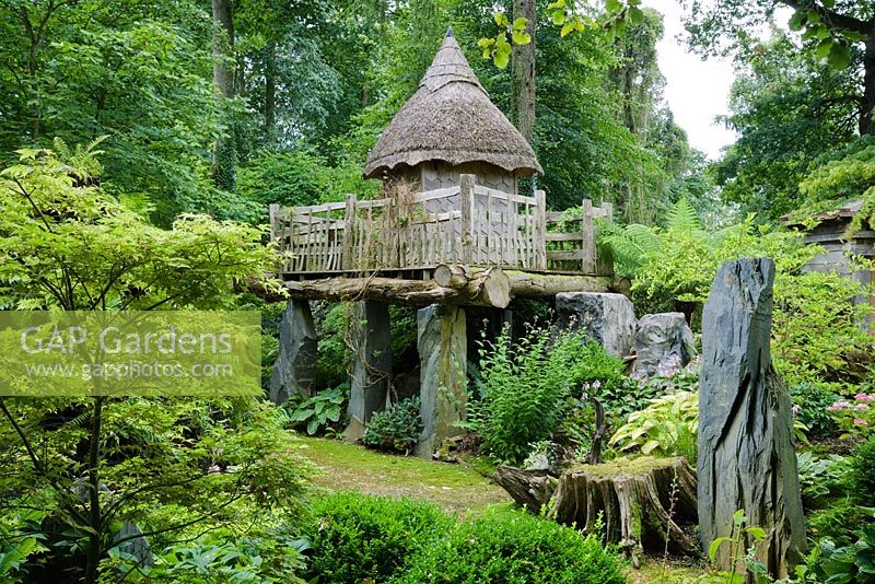 The thatched tree house 'Hollyrood House' in the Stumpery. The house stands on a rustic platform of oak supported by shards of Welsh slate. Highgrove Garden, August 2007. 