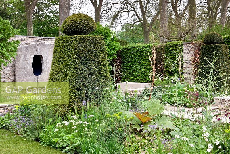 Topiary and flowerbeds in country garden 