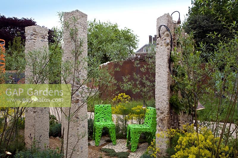Pudding stone columns create a sustainable landscape, with chairs made from recycled bottles. A mix of ferns and Mediterranean planting - The Renault Garden, RHS Chelsea Flower Show 2012