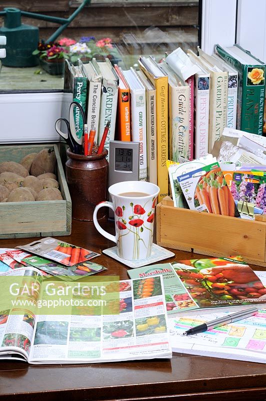 Gardeners desk with books, seed catalogues and packets of seeds, February