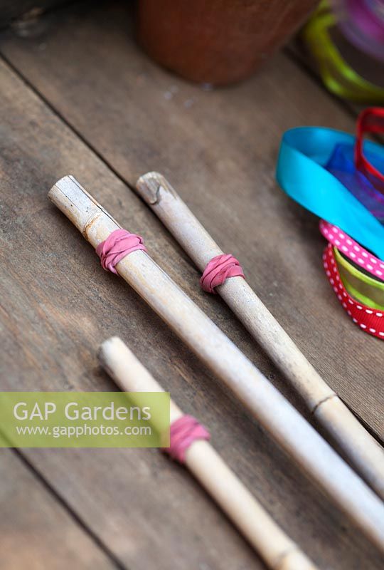 Making garden tealight holders - Put elastic bands around the top of bamboo canes to act as stoppers for the plant pots