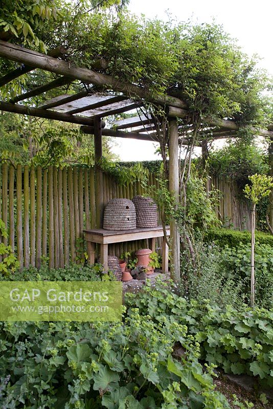 Herb garden with beehives on table under the rose pergola, De Romantische tuin - The Romantic Garden of Dina Deferme and Tony Pirotte