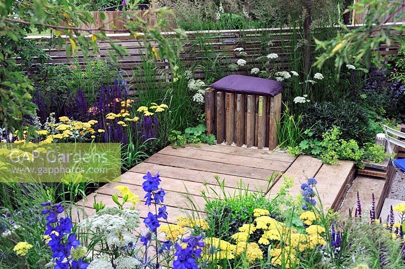 Blue and yellow planting around decking area with unusual seat - Our First home Our first garden, Hampton Court Palace flower show 2012