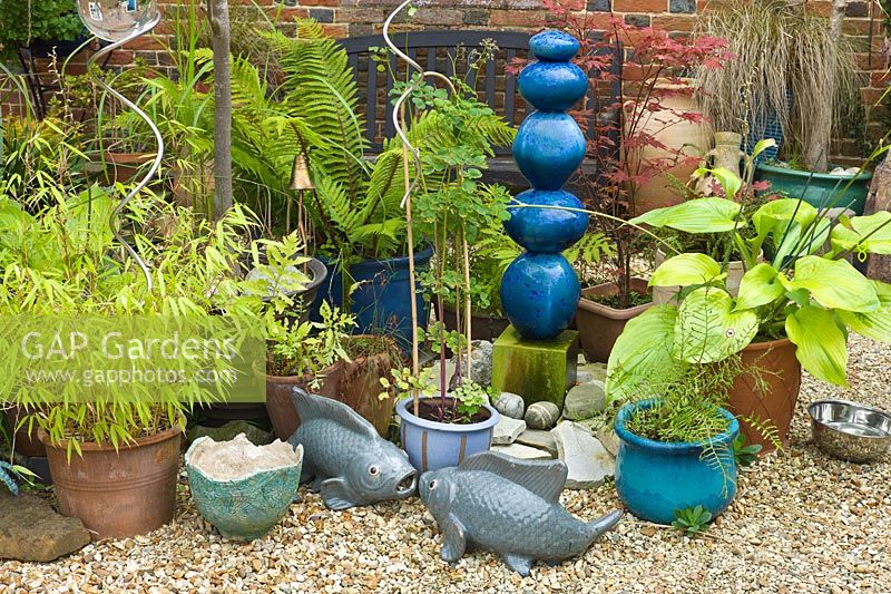 Gravel garden with container planting and decorative ornaments. 