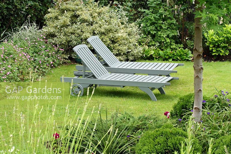 Painted wooden recliners on a lawn of an urban garden with a country feel