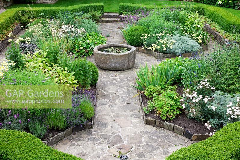 The sunken garden enclosed with Buxus curving hedges, with central antique stone trough raised pond water feature. Draught tolerant plants include Anthemis tinctoria, Erysimum 'Bowles' Mauve', Iris', Bergenias, Lavandula, Sage,Echinops, Artemesia and Achillea.