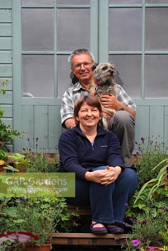 Barry and Mandy Milton on the steps of their summerhouse with their border terrier, Monty - The Lizard, Wymondham, Norfolk