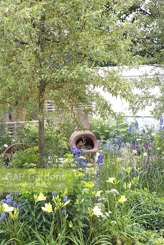 Our First Home, Our First Garden. Hampton Court Flower Show 2012. Planting includes Erygium 'Sapphire Blue', Hemerocallis 'Missouri Beauty' nepeta and thyme. Open-fire chiminea and Amelanchier canadensis.