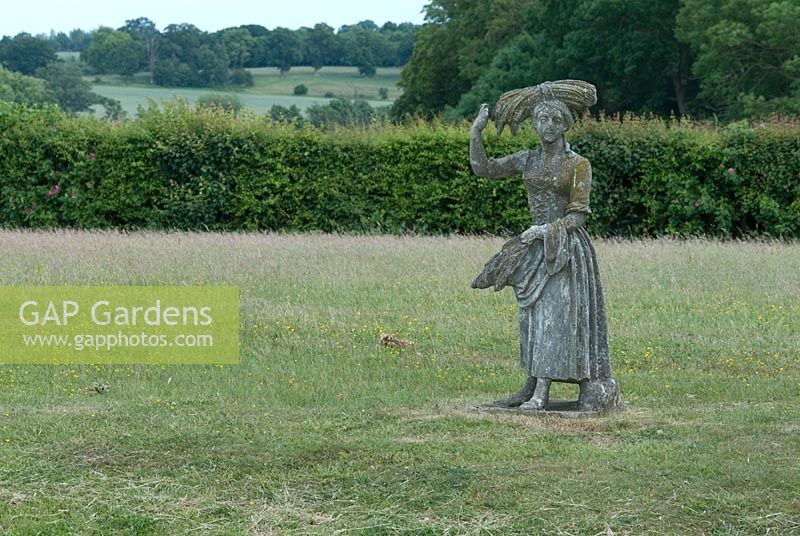 Stone statue of a girl with harvested corn at Wood Farm, Suffolk. June